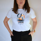 A woman wearing a white short-sleeve graphic T-shirt with a stylized lotus and fish design and the word 'Udaan' printed on the chest, paired with black pants against a plain light background.